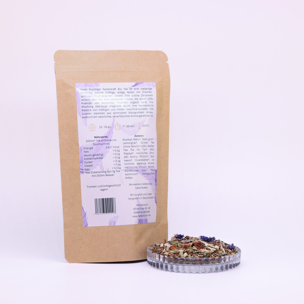 100g-Beutel Bio-Rooibostee ‚Fruchtige Fastenkraft‘ mit orange-lilanem Etikett Rückseite, daneben Glasschale mit losem Tee.