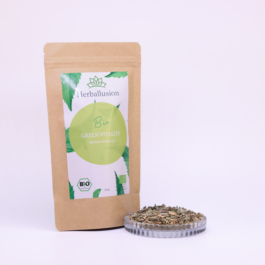 100g-Beutel Bio-Matetee ‚Green Vitality‘ mit gelb-grünem Etikett, daneben Glasschale mit losem Tee.