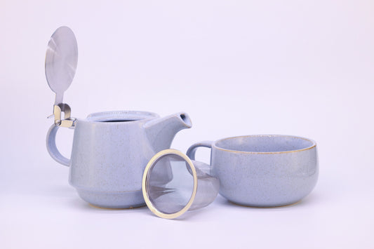 Tea-for-one Set in glänzend blau steht komplett auseinander gebaut auf weißem Hintergrund. Man sieht die Teekanne, die Teetasse und das Teesieb