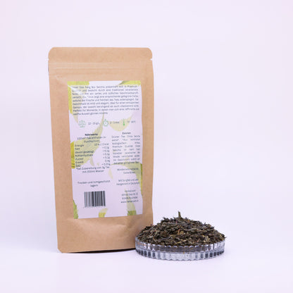 100g-Beutel Bio-Grüntee ‚Dao Feng Bio Sencha‘ mit gelb-grünem Etikett Rückseite, daneben Glasschale mit losem Tee.