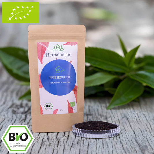 100g-Beutel Bio-Schwarztee ‚Friesengold´ mit rot-blauem Etikett, daneben Glasschale mit losem Tee. Im Hintergrund Zutaten zu sehen sowie Bio und EU Zertifizierung.