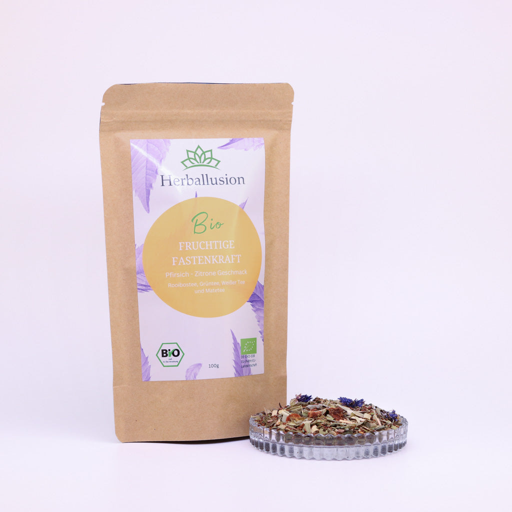100g-Beutel Bio-Rooibostee ‚Fruchtige Fastenkraft‘ mit orange-lilanem Etikett, daneben Glasschale mit losem Tee.