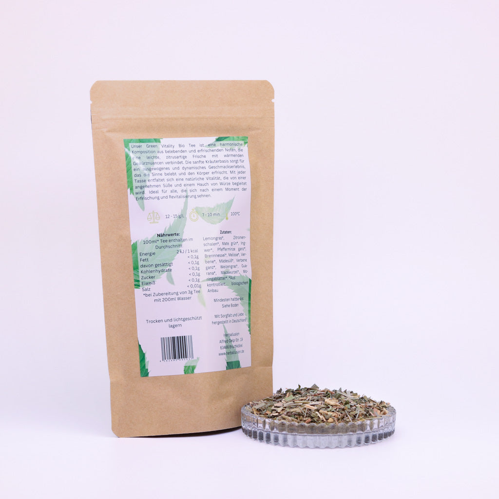 100g-Beutel Bio-Matetee ‚Green Vitality‘ mit gelb-grünem Etikett Rückseite, daneben Glasschale mit losem Tee.
