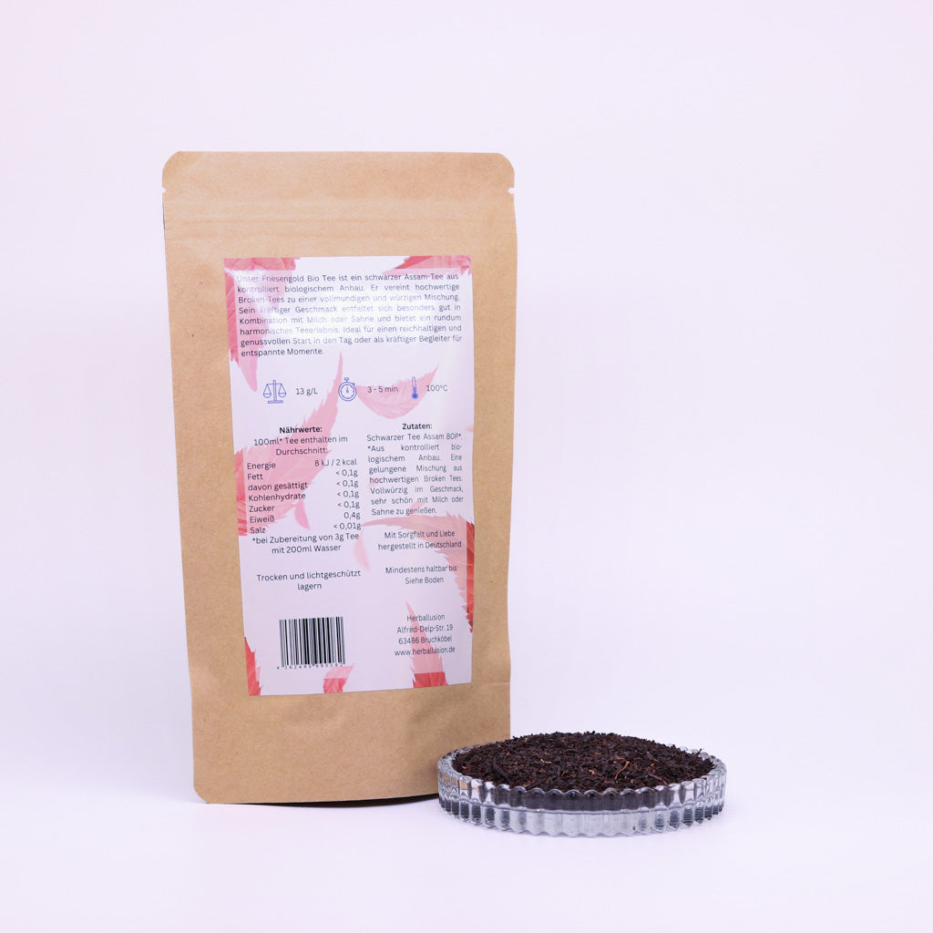 100g-Beutel Bio-Schwarztee ‚Friesengold´ mit rot-blauem Etikett Rückseite, daneben Glasschale mit losem Tee.