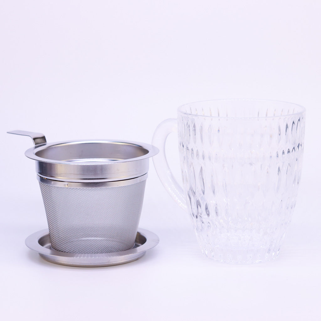 Nachtmann Teetasse Ethno steht auf weißem Hintergrund. Daneben steht das passende Teesieb