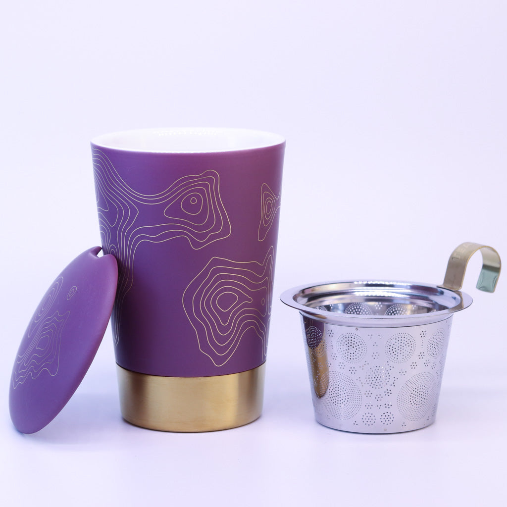 Teaeve Precious in lila steht auseinander gebaut auf weißem Hintergrund. Daneben steht das Teesieb und der Deckel der Tasse