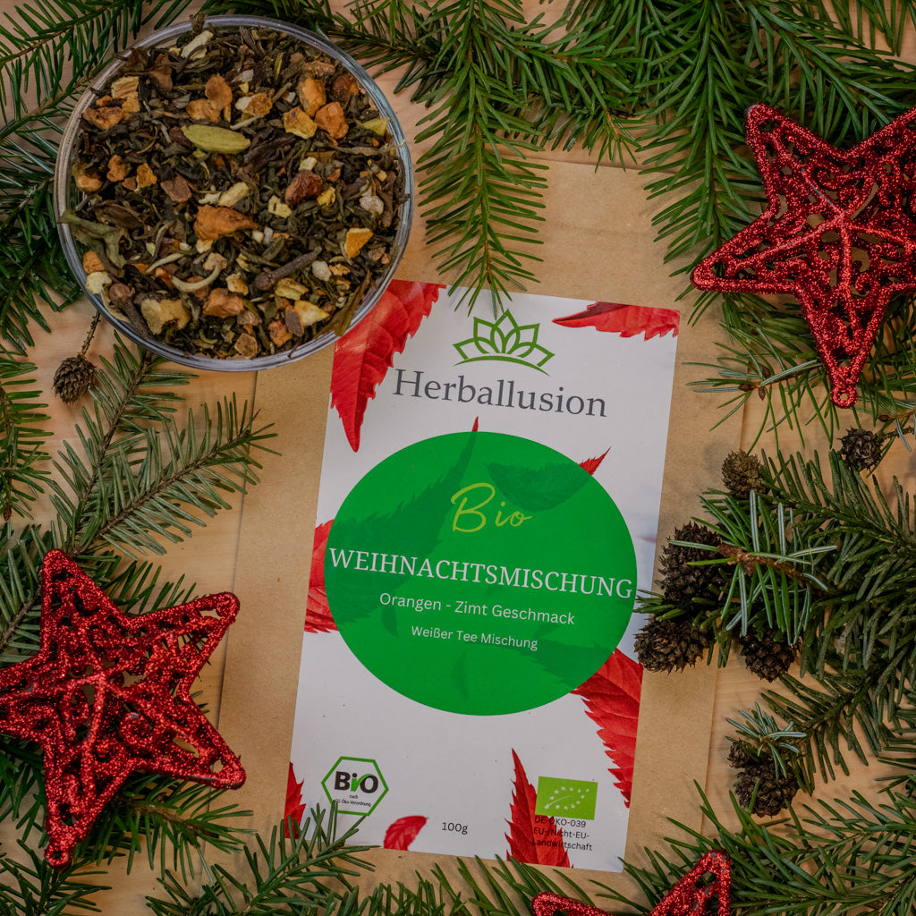 100g Beutel des Bio-Tees Weihnachtsmischung auf Holzhintergrund mit weihnachtlicher Deko und Glasschale mit losem Tee