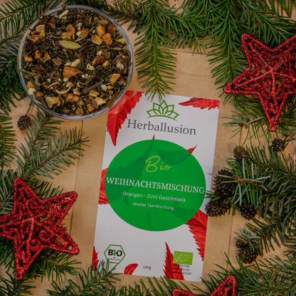 100g Beutel des Bio-Tees Weihnachtsmischung auf Holzhintergrund mit weihnachtlicher Deko und Glasschale mit losem Tee