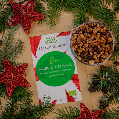 100g Beutel des Bio-Tees Weihnachtszauber auf Holzhintergrund mit weihnachtlicher Deko und Glasschale mit losem Tee